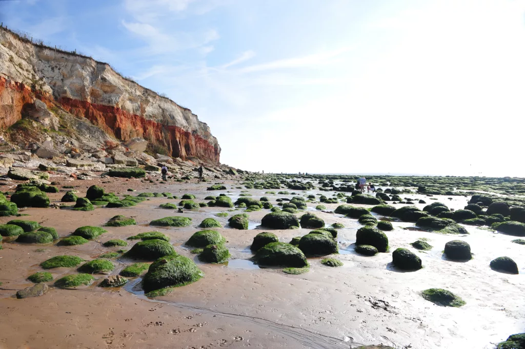Hunstanton beach at low tide, a group of people rock pooling in the background