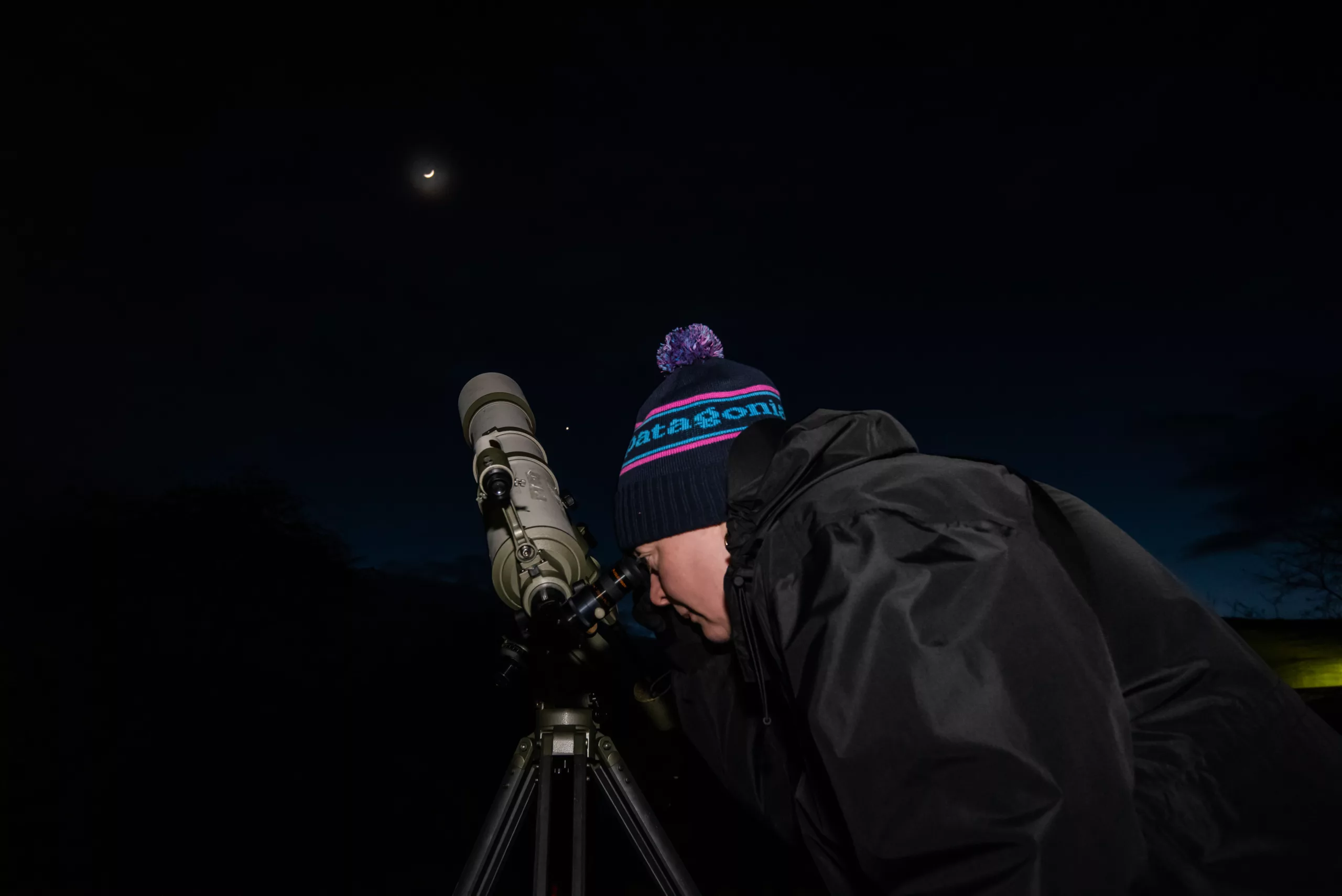 Person looking through a telescope at the moon