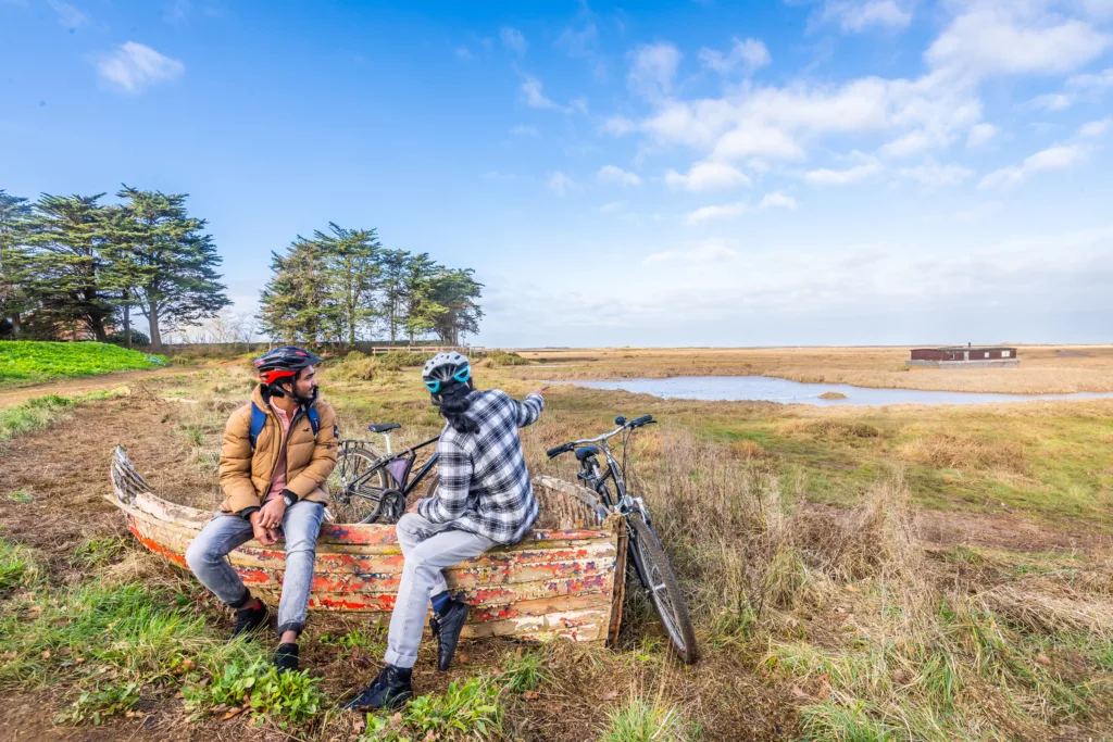 Two men with bikes resting on the remnants of a wooden boat