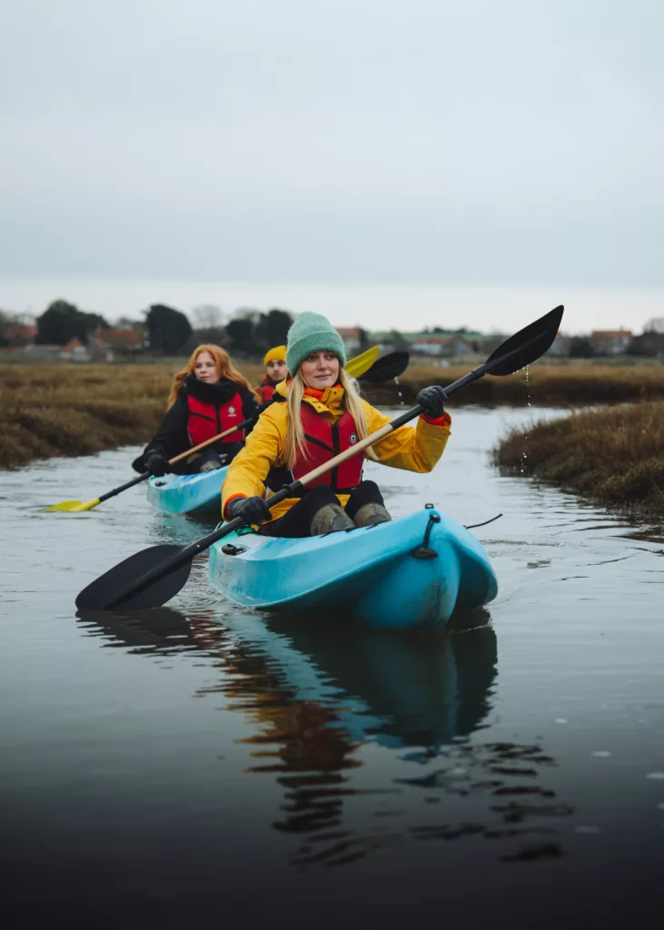 Three people kayaking on along a river