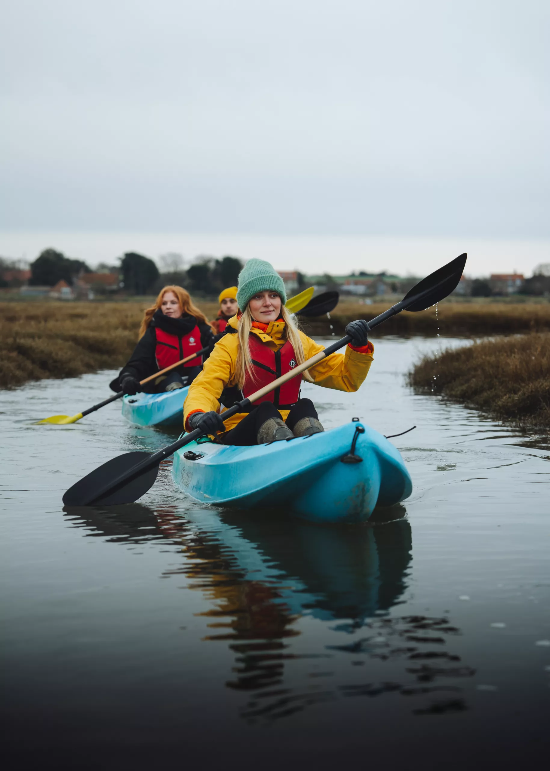 Three people kayaking on along a river